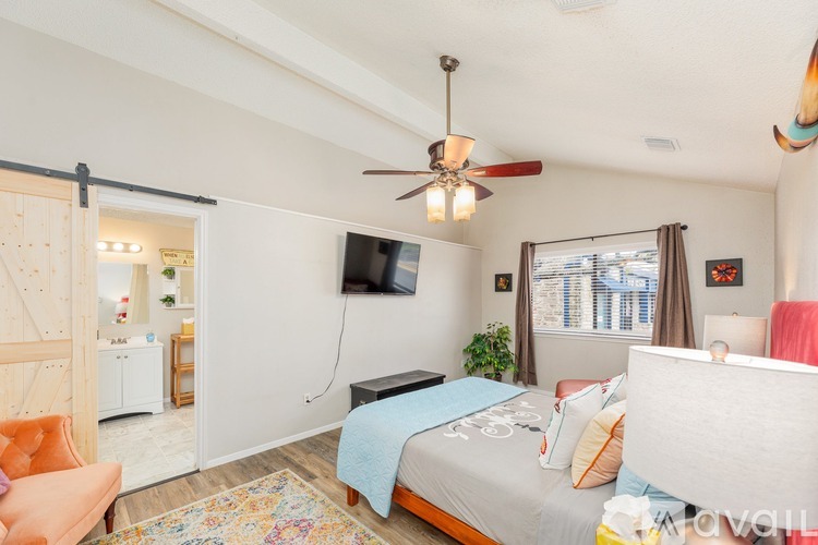 A bedroom with a bed, chair, and sliding door.