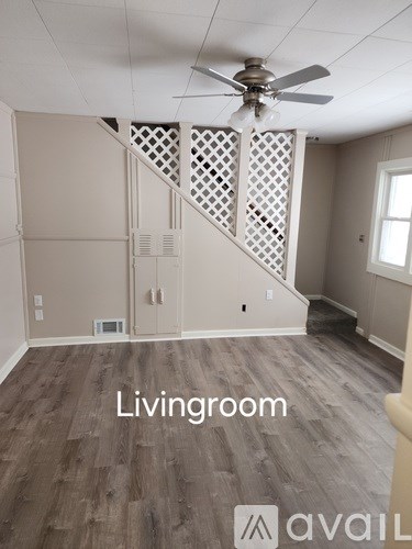 A living room with a wooden floor and a staircase with a lattice design.
