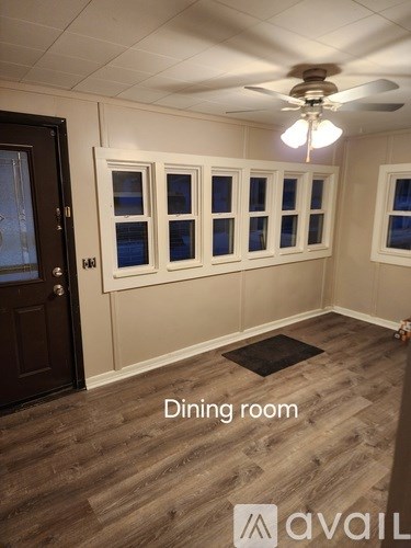 A dining room with a ceiling fan and wooden flooring.