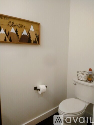 A bathroom with a wooden sign that says "The Adventure" above a toilet.