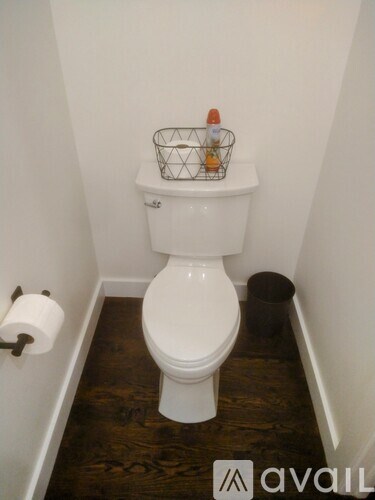 A white toilet with a basket on top of it.