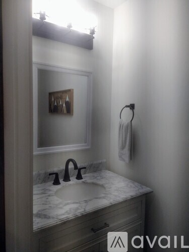 A bathroom with a marble countertop and a framed picture on the wall.
