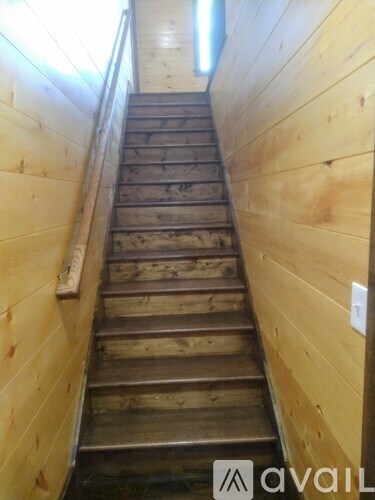 A wooden staircase with a light switch on the wall.