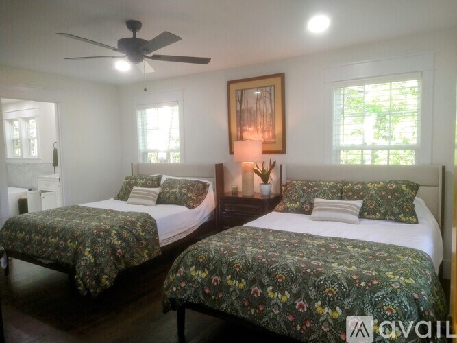 Two beds with floral bedspreads in a room with a ceiling fan.