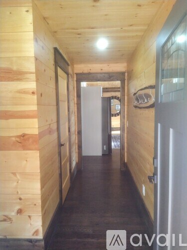 A long hallway with wood paneling and a white door at the end.