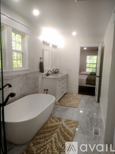 A bathroom with a tub, sink, and window.