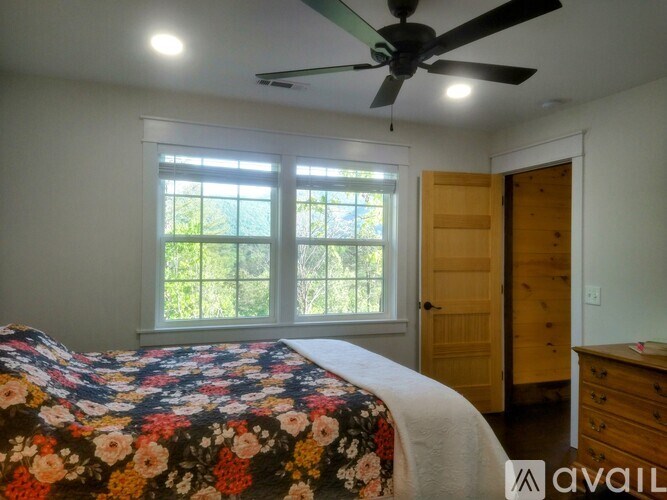 A bedroom with a floral bedspread and a ceiling fan.