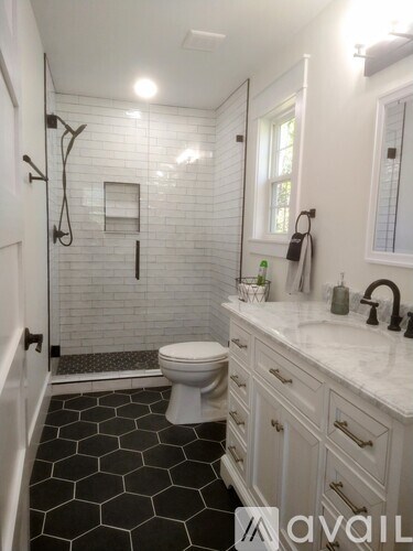 A white bathroom with black hexagonal tiles on the floor.