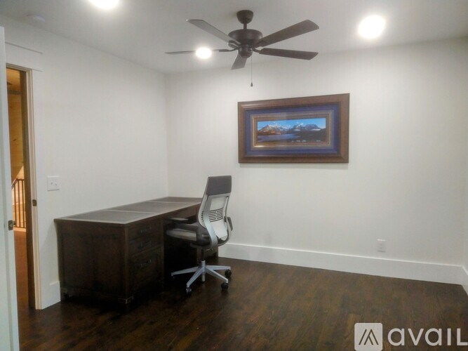 A room with a ceiling fan and a painting on the wall.