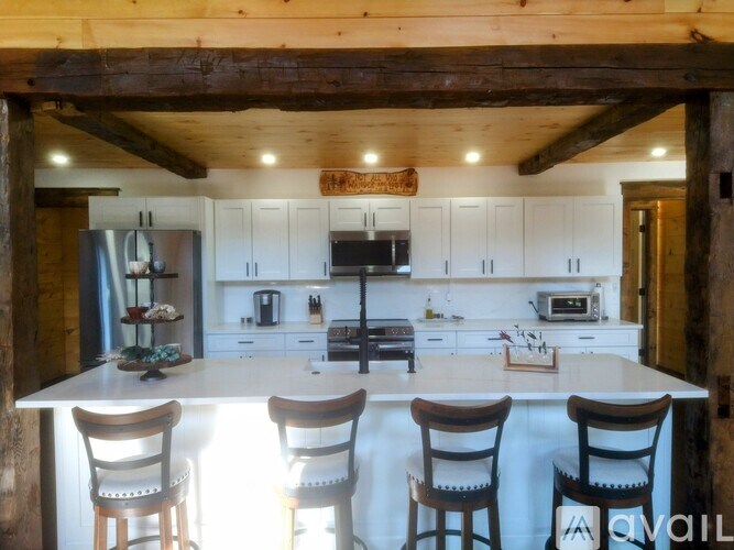 A kitchen with white cabinets and a wooden ceiling.