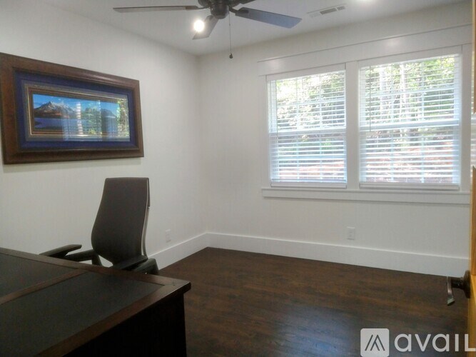 A room with a desk, chair, and a painting on the wall.