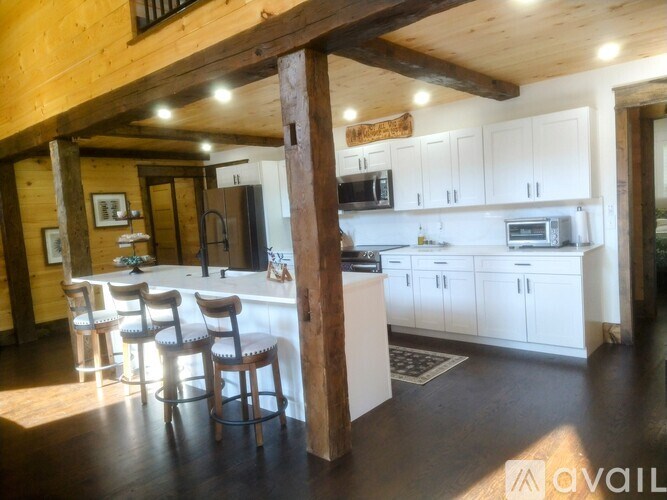 A kitchen with white cabinets and a wooden beam ceiling.