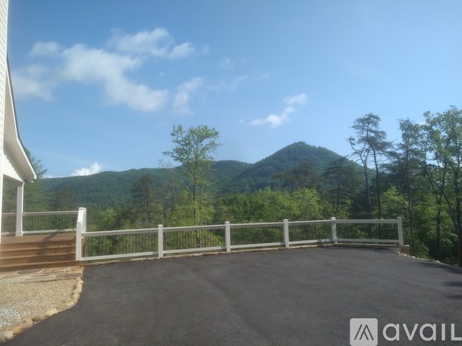A paved area with a white fence and a mountain in the background.