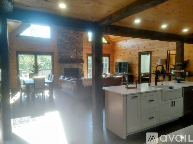 A well-lit kitchen and dining area with wooden beams and a brick fireplace.