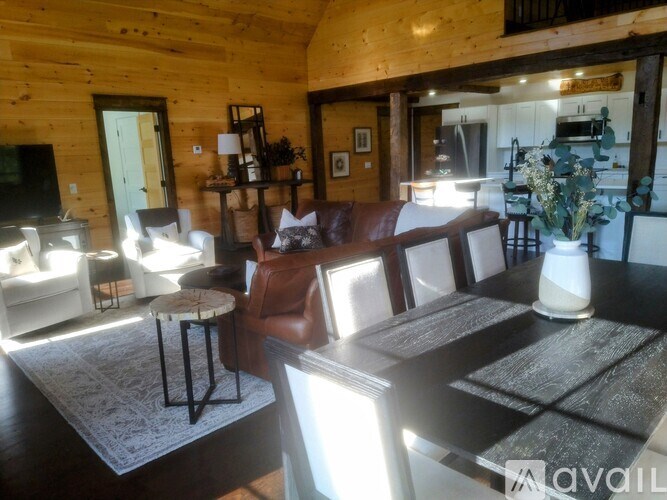 A living room with a brown leather couch and a wooden table.