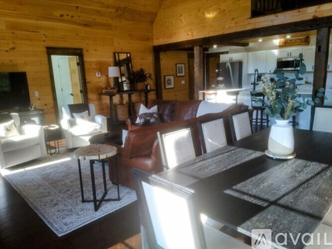 A living room with a brown leather couch and a wooden table.