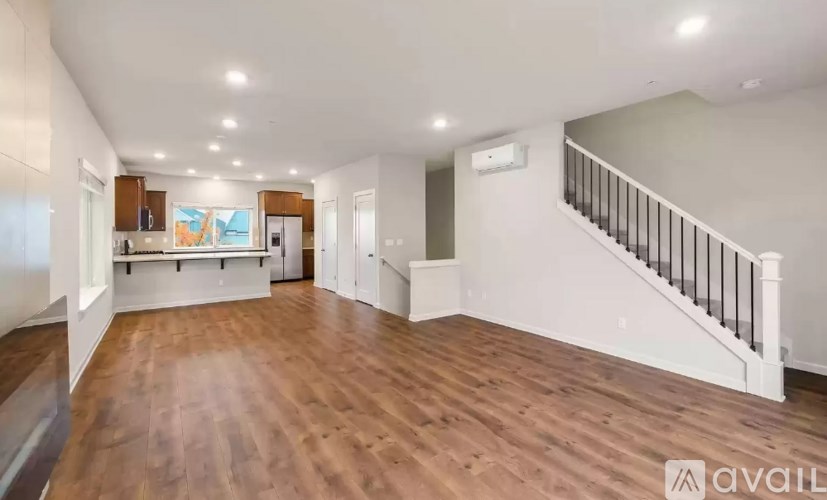 A spacious room with wooden floors and a staircase with a railing.