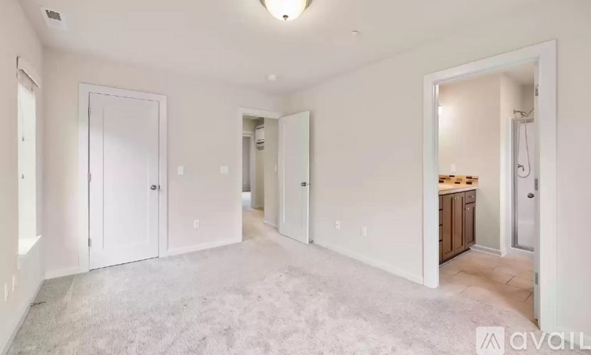A spacious room with white walls and carpeted floor.