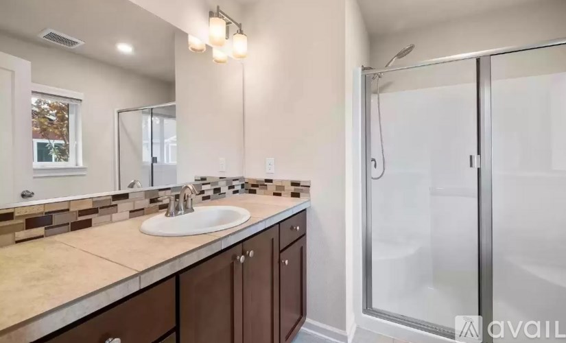 A bathroom with a sink, mirror, and shower.