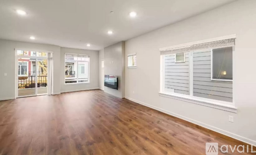 A spacious room with wooden floors and white walls.