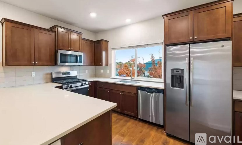 A kitchen with wooden cabinets and stainless steel appliances is available for rent.