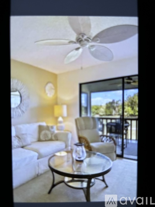 A living room with a white couch, a coffee table, and a ceiling fan.