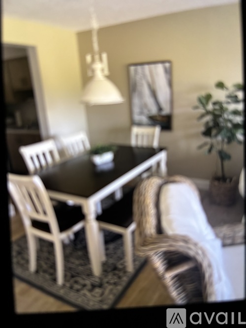 A black dining table with four chairs and a rug.