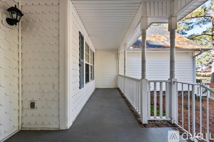 A white porch with a black lantern on the wall.