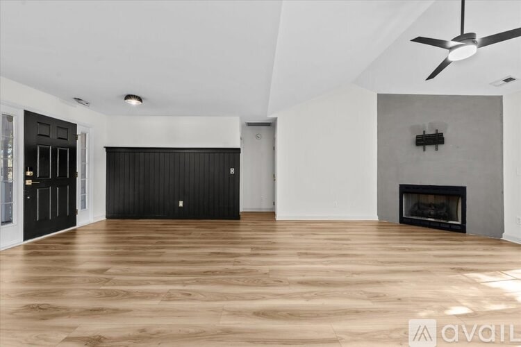 A spacious room with a fireplace and a ceiling fan.