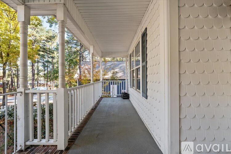 A porch with a white railing and a white wall with a pattern on it.
