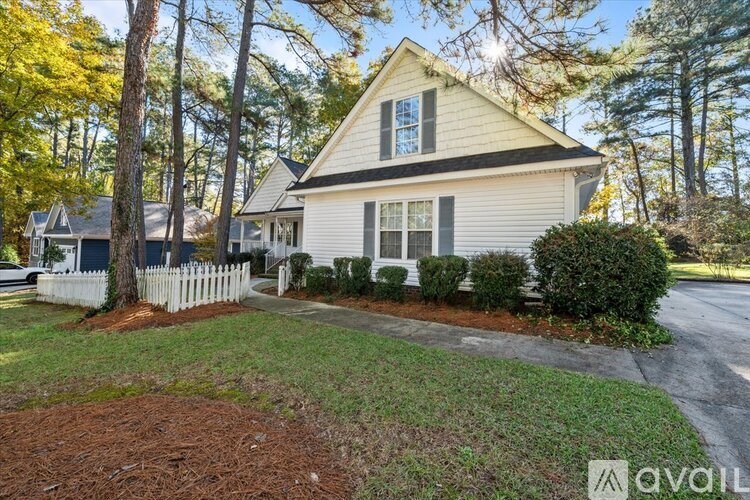 A house with a white picket fence and a driveway in front.