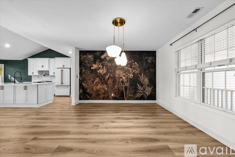 A modern kitchen with white cabinets and a wooden floor.