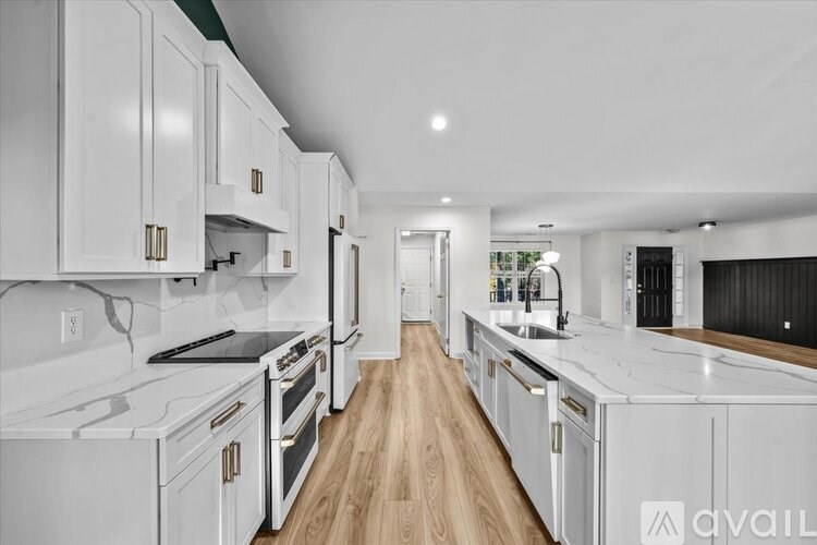 A modern kitchen with white appliances and wooden floors.