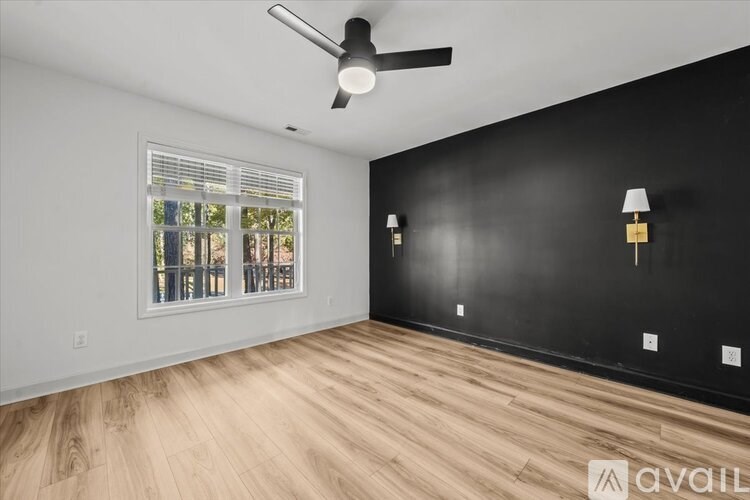 A room with a ceiling fan, wooden flooring, and a window with blinds.