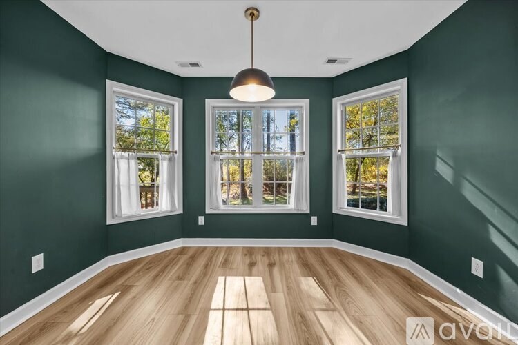 A room with three windows and wooden floors.