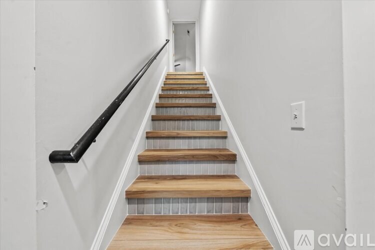 A staircase with wooden steps and a black handrail.