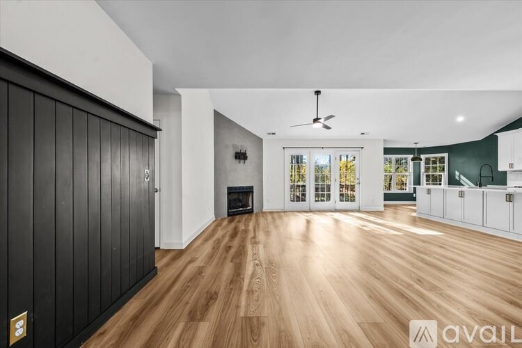 A spacious room with wooden flooring and a fireplace.