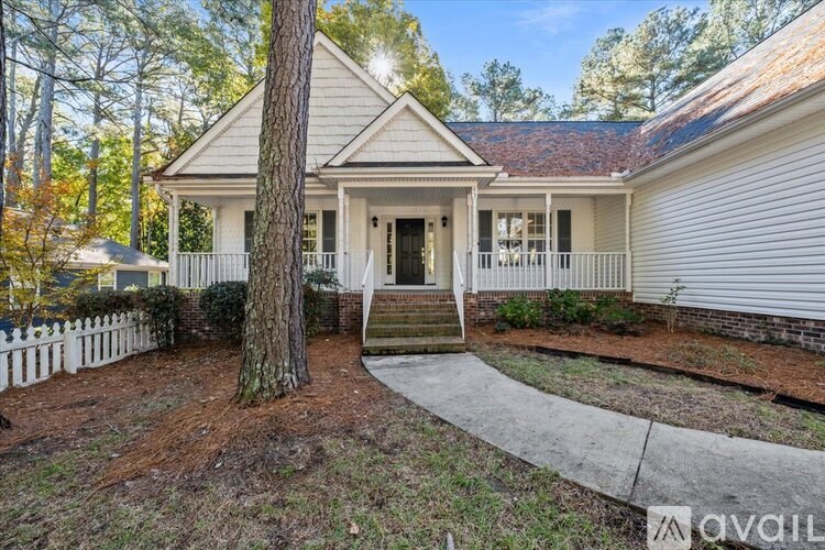 A house with a white picket fence and a tree in front.