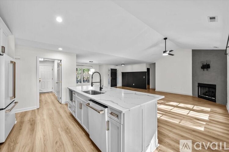 A modern kitchen with white appliances and wooden flooring.