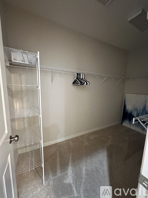 A room with a white door and a white shelf with clothes hanging on it.