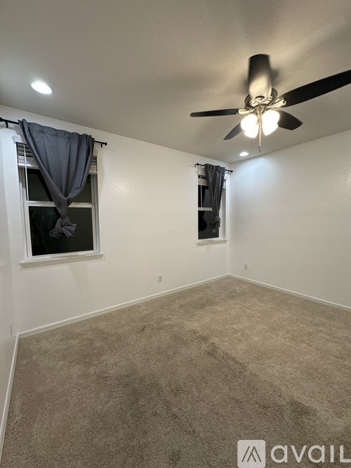 A room with a ceiling fan and carpeted floor.