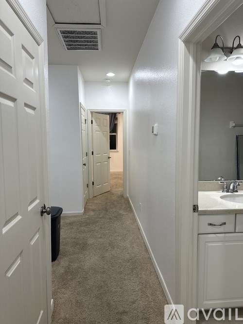 A long hallway with white doors and carpeting.