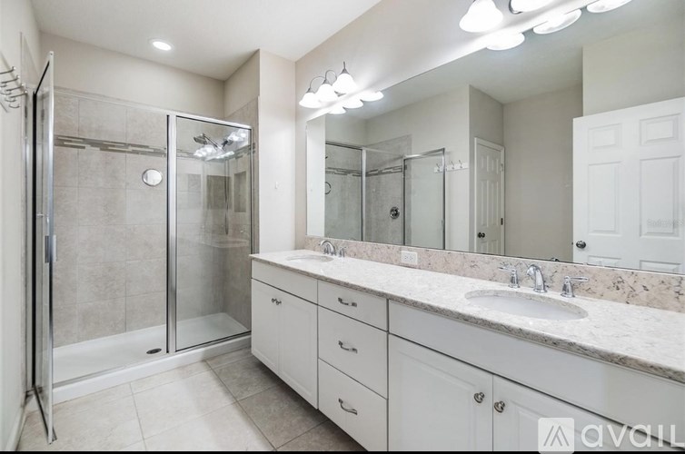 A bathroom with a walk-in shower and double sinks.