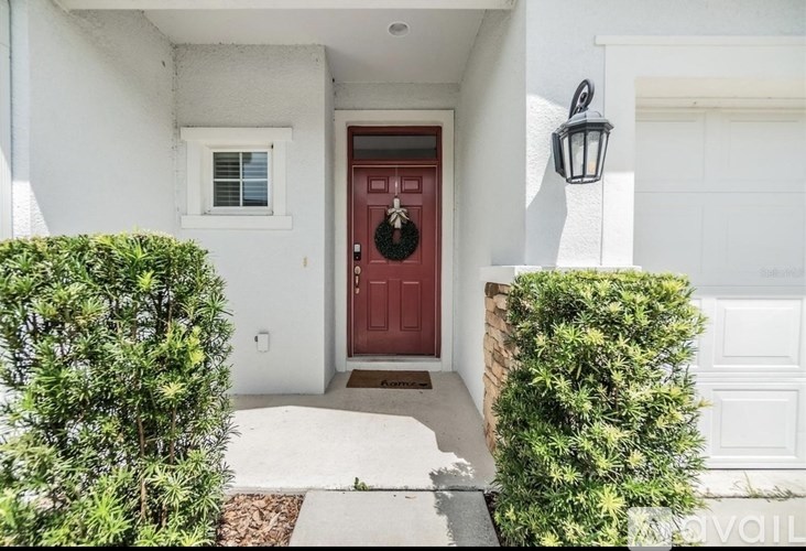 A red door is the centerpiece of this white house entrance.