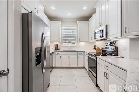 A kitchen with white cabinets and a stainless steel refrigerator.