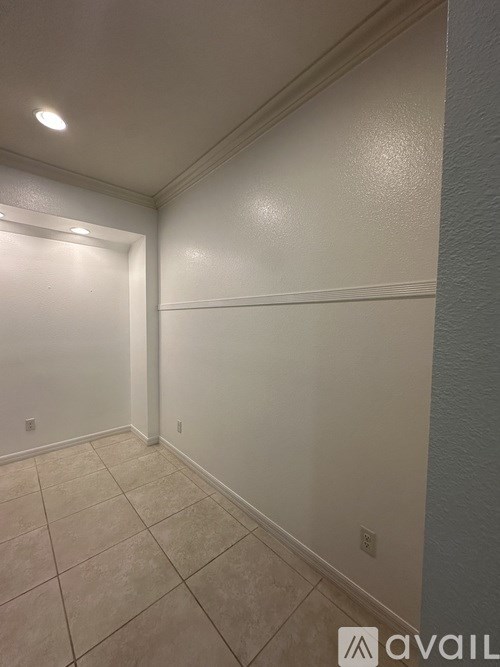 A hallway with tiled flooring and white walls.