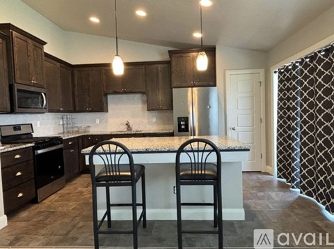 A kitchen with dark brown cabinets and a granite countertop.