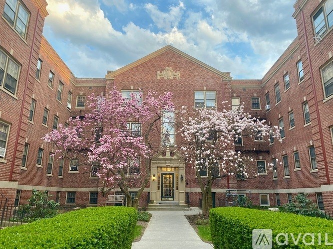 A brick building with a tree with pink flowers in front.