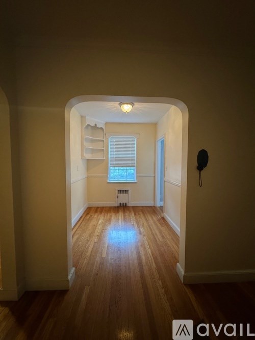 A hallway with wooden floors and white walls.
