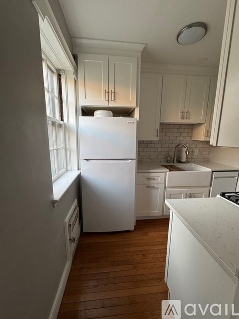 A white fridge in a kitchen with wooden floors.